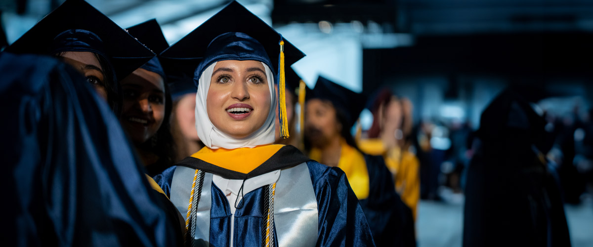 Female student smiling in a crowd of fellow graduates.