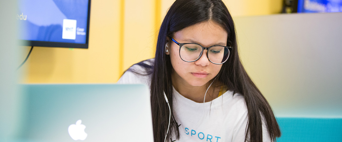 Girl in glasses using a Mac Book.