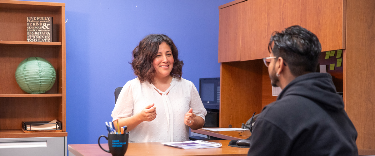 A student sits at a desk to speak with a member of New York Tech's Office of the Bursar.