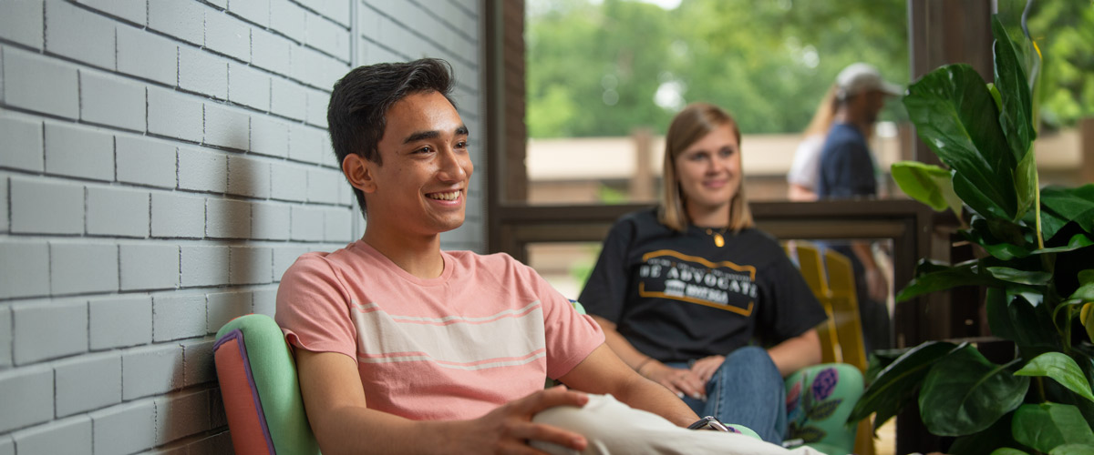 Two students lounge inside a building on New York Tech's Long Island Campus.