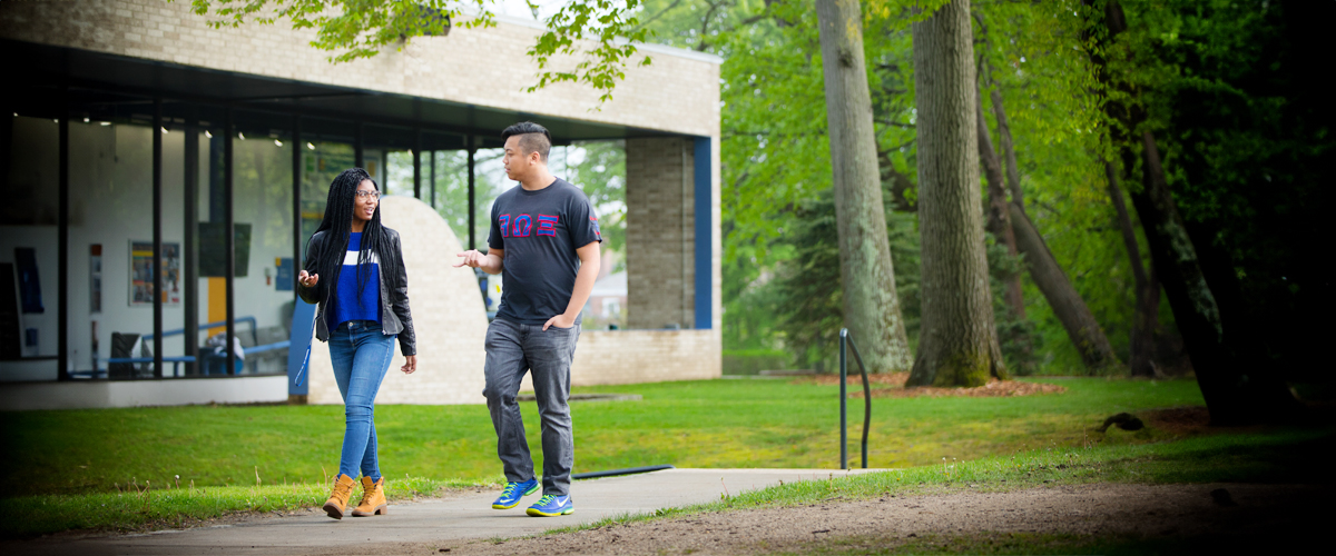 Two students are walking along a path at New York Tech's Long Island campus.