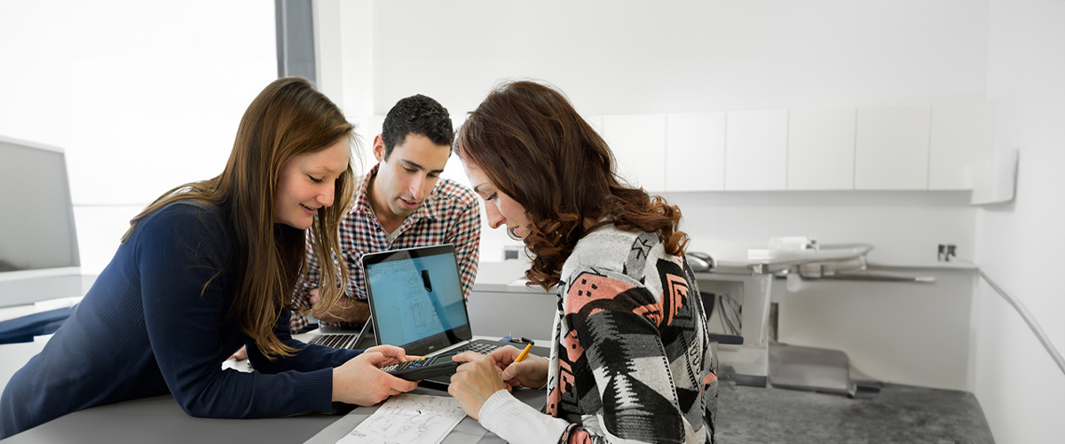 Group of people surrounding a computer in an office.