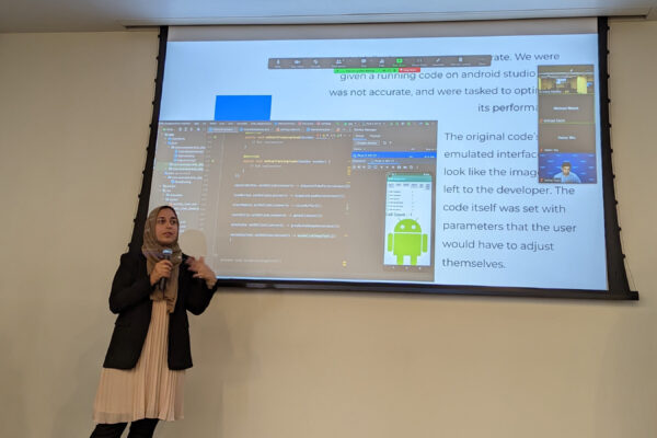 Three student presenting their project board to a classroom.