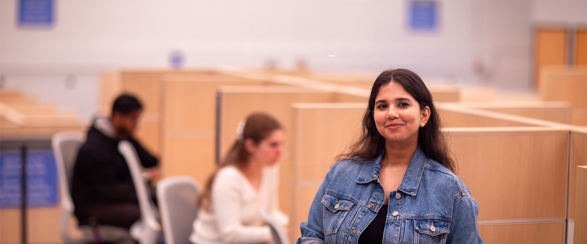 A student stands among others in a study area on campus.