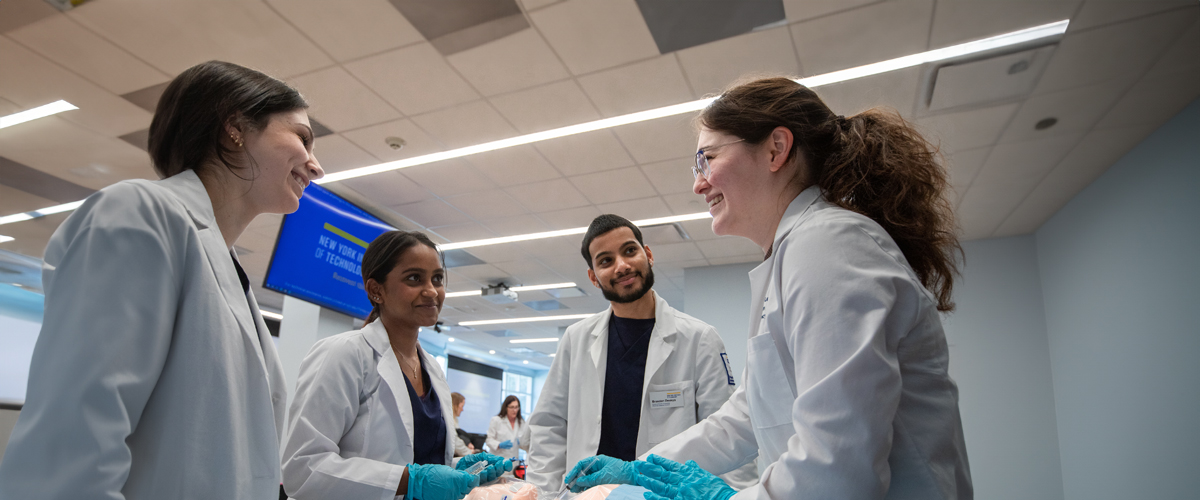 A group of students in the School of Health Professions chat in a classroom.