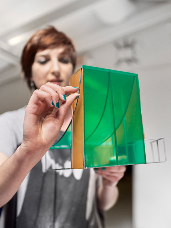 A student is working on a green and yellow sculpture in a design studio.