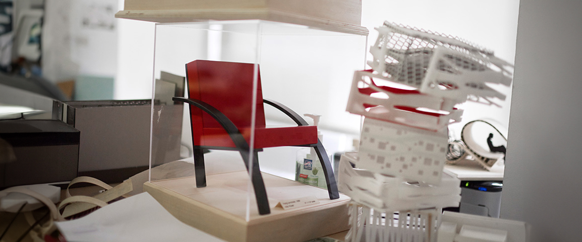 A red chair in a glass case is on display for interior design.