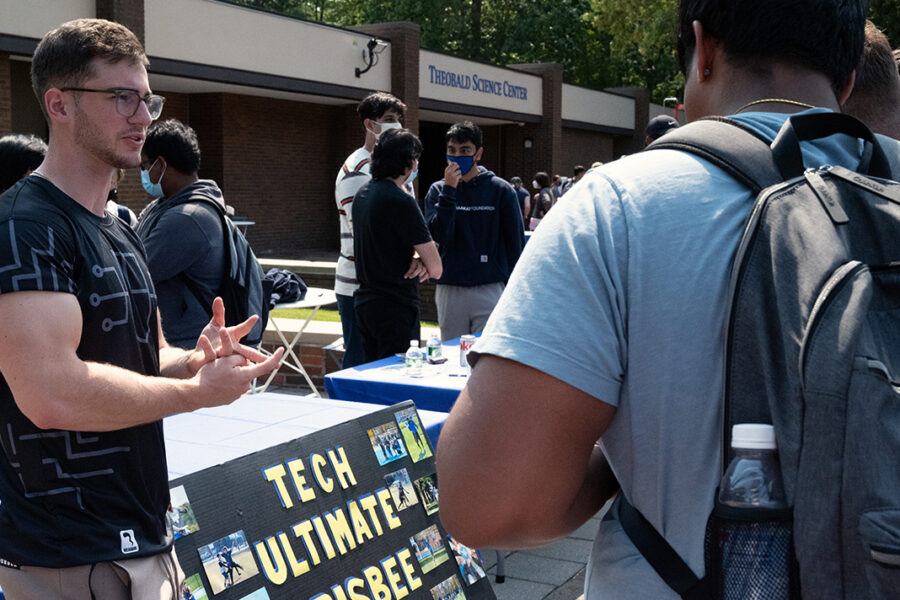 Student at booth talking to other student.