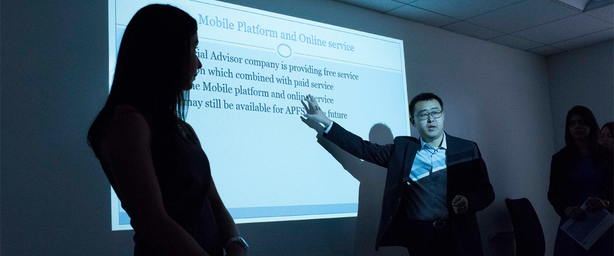 An instructor presenting in a dark classroom.