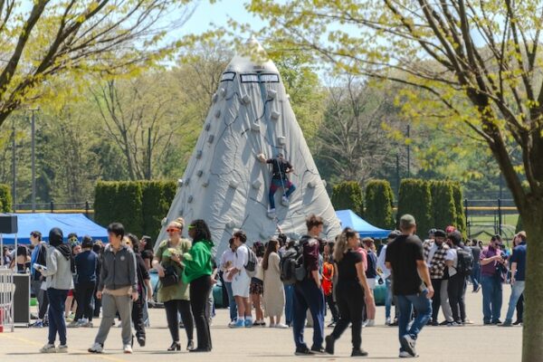 Crowd of people around rock climbing area.