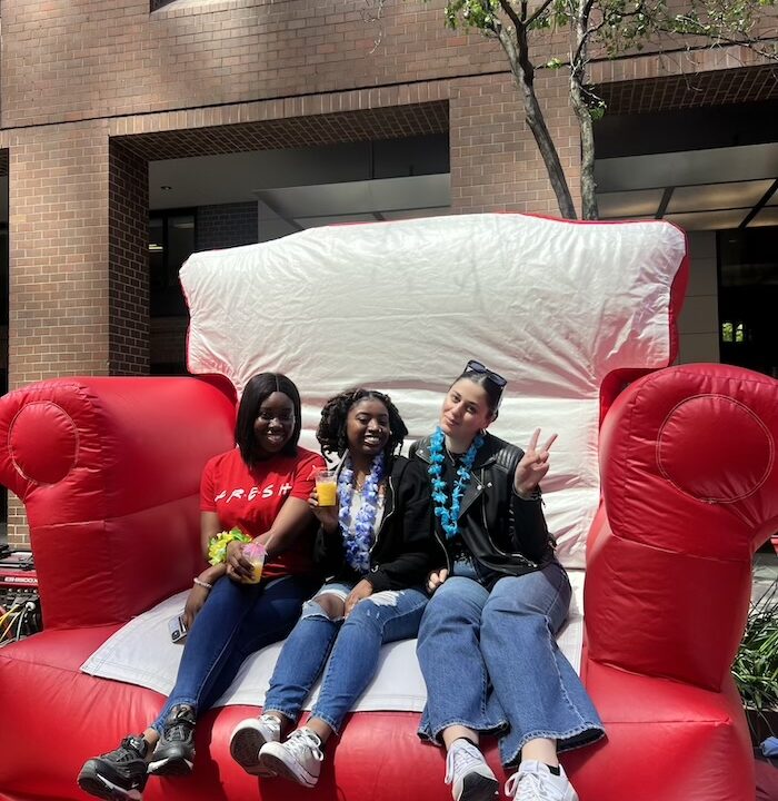 Three students on a giant chair prop posing