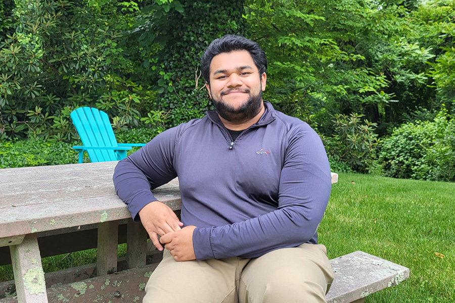 New York Tech student Alex Menachery sitting on a bench