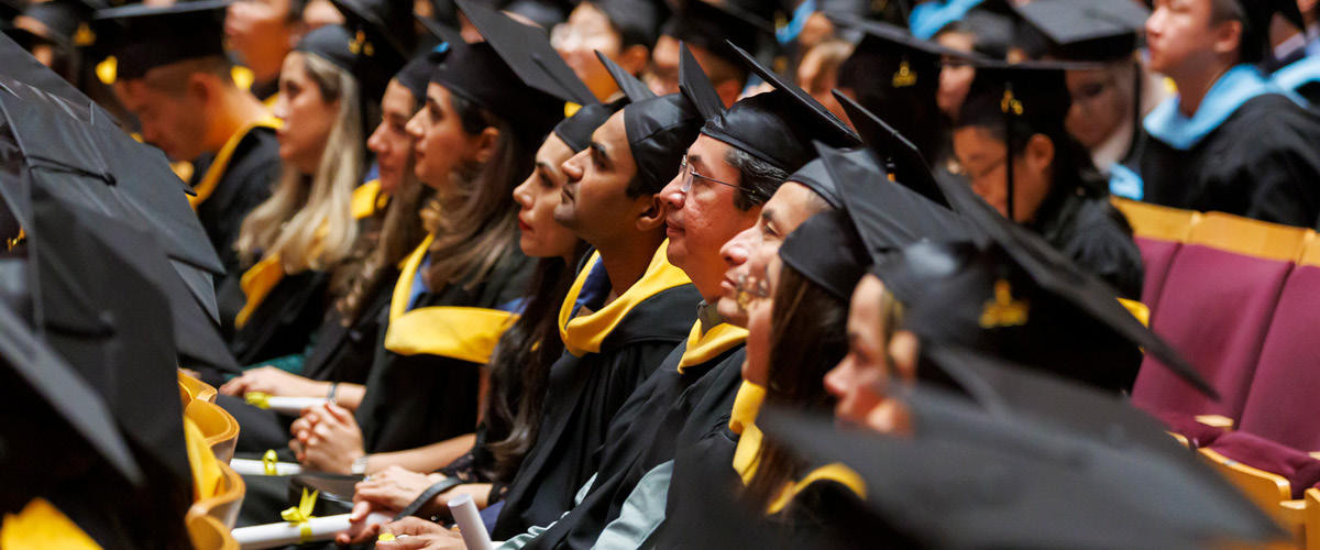 Graduates wearing caps and gowns sitting in an auditorium