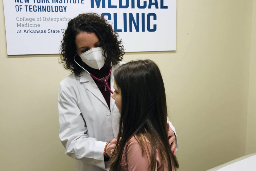 Doctor wearing a mask checking a young patient.