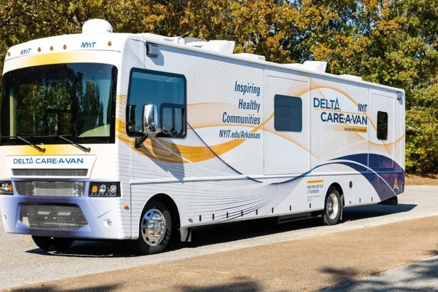 NYITCOM Bus on a road during a sunny day.