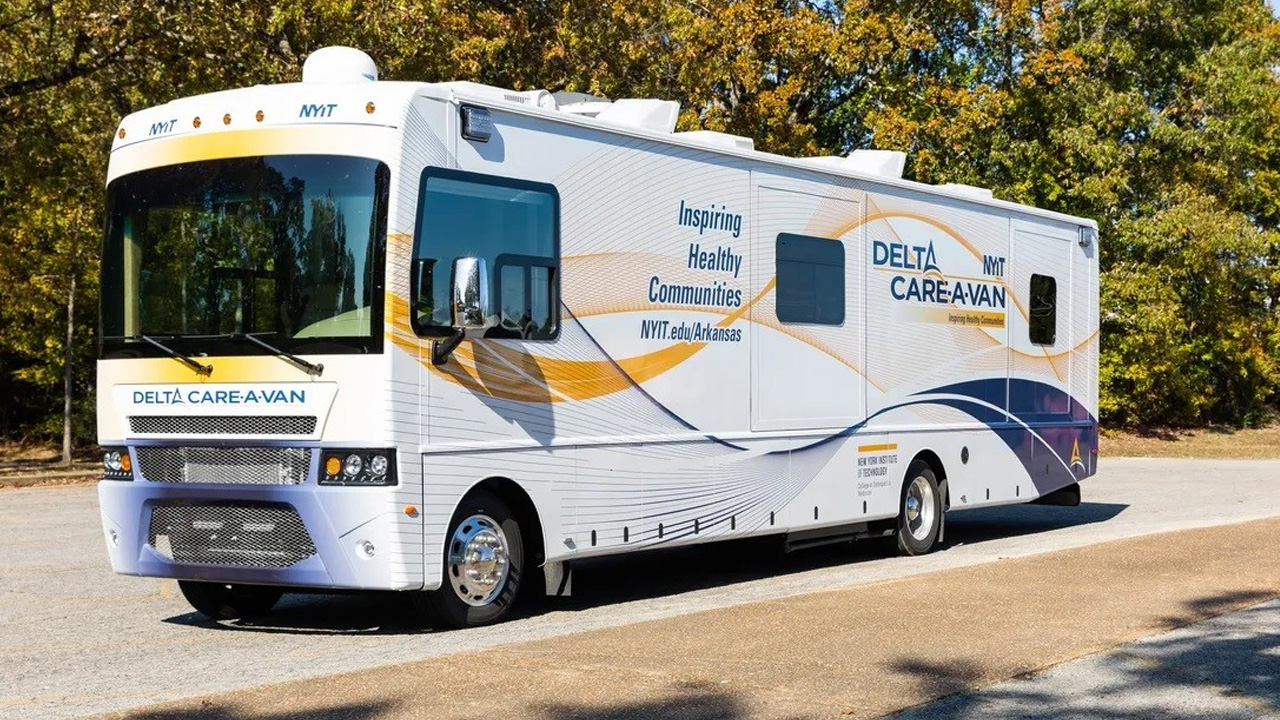 NYITCOM Bus on a road during a sunny day.