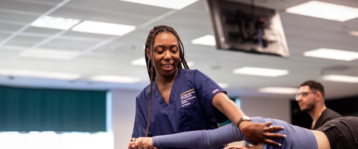 A medical student training and making adjustments to a patient on the table.