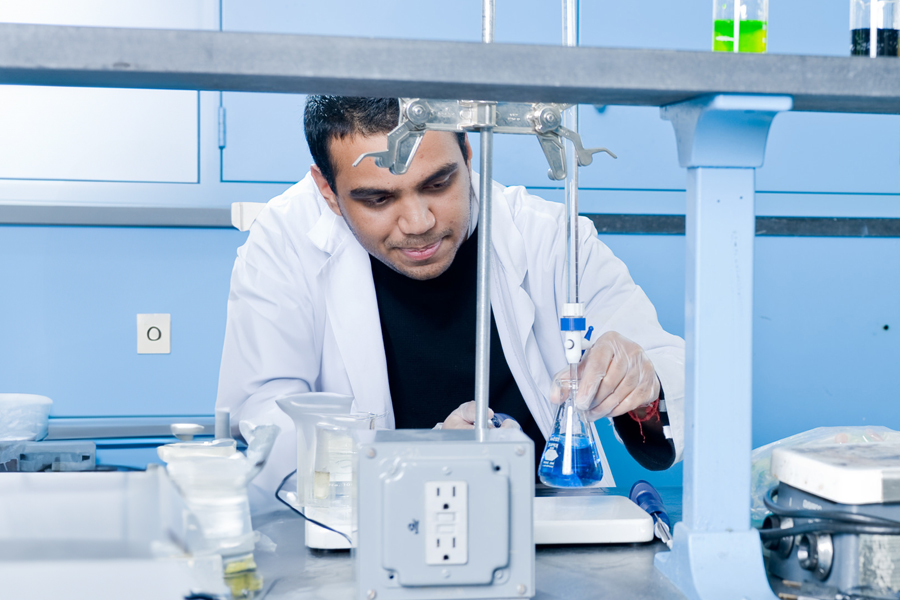 A man looking at a beaker in a lab